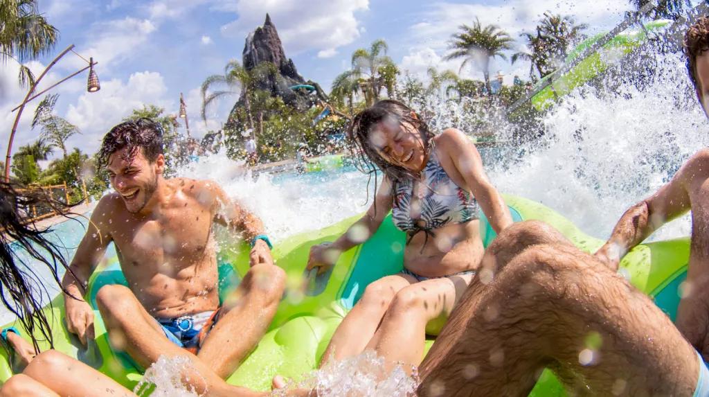 Guests in a rubber raft getting splashed in front of the volcano at Volcano Bay