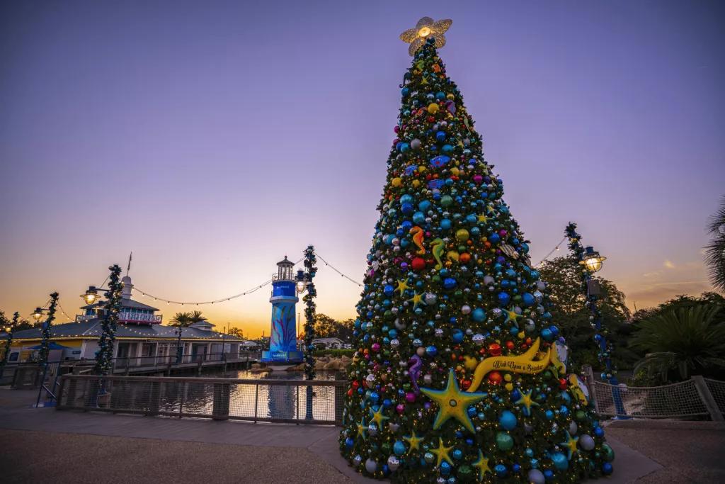 A decorated Christmas tree in front of the SeaWorld lighthouse while the sun is setting