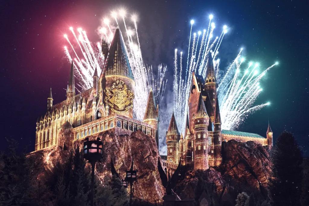 Hogwarts Castle lit up by projection mapping with fireworks in the background