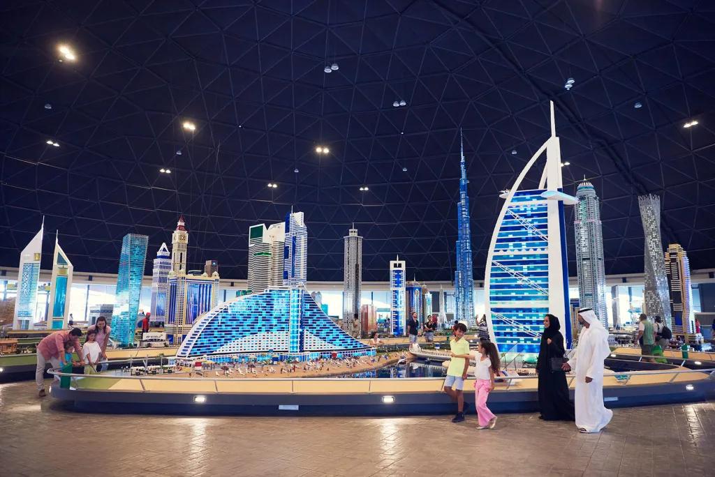A family walking through lego sculptures of iconic Dubai skyscrapers including the Burj Al Arab and Jumeirah hotel next door.