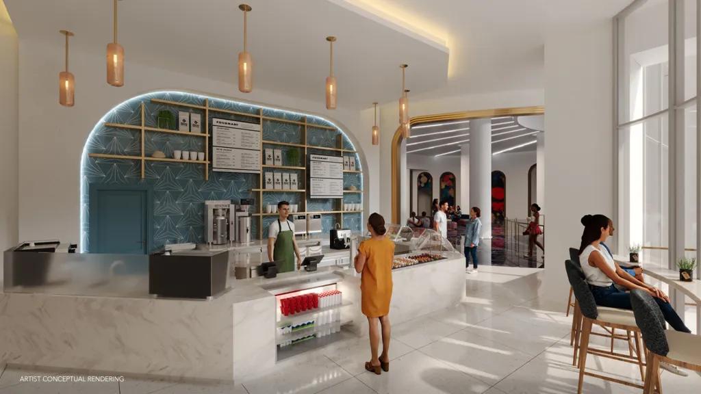 Modern Mediterranean style cafe with white counters, gold lighting, a glass case with desserts in. People are sat on gold seats looking outside windows overlooking Epic Universe.  