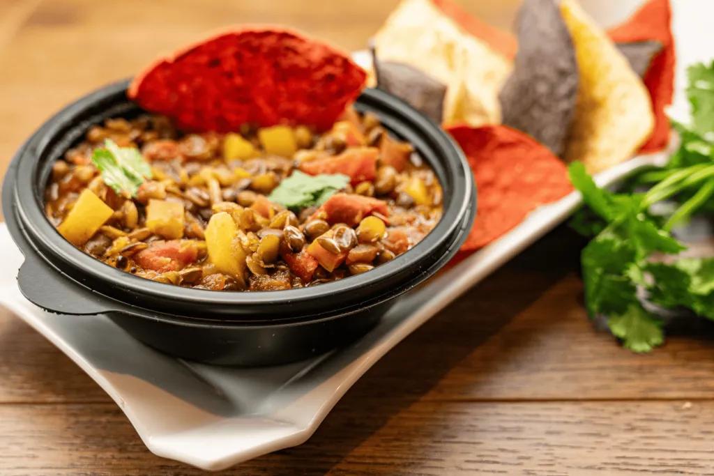A bowl of lentil chili with tortilla chips on the side