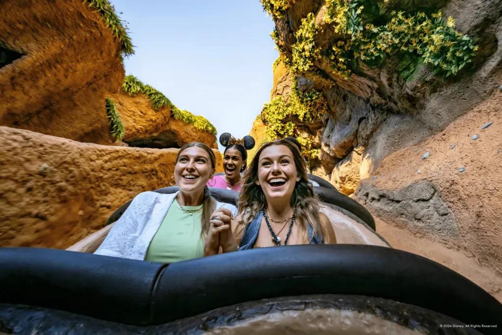 Zwei junge Frauen halten sich an den Händen und lächeln während Sie auf einer Wasserrutsche sind, kurz vor der Abfahrt steht.