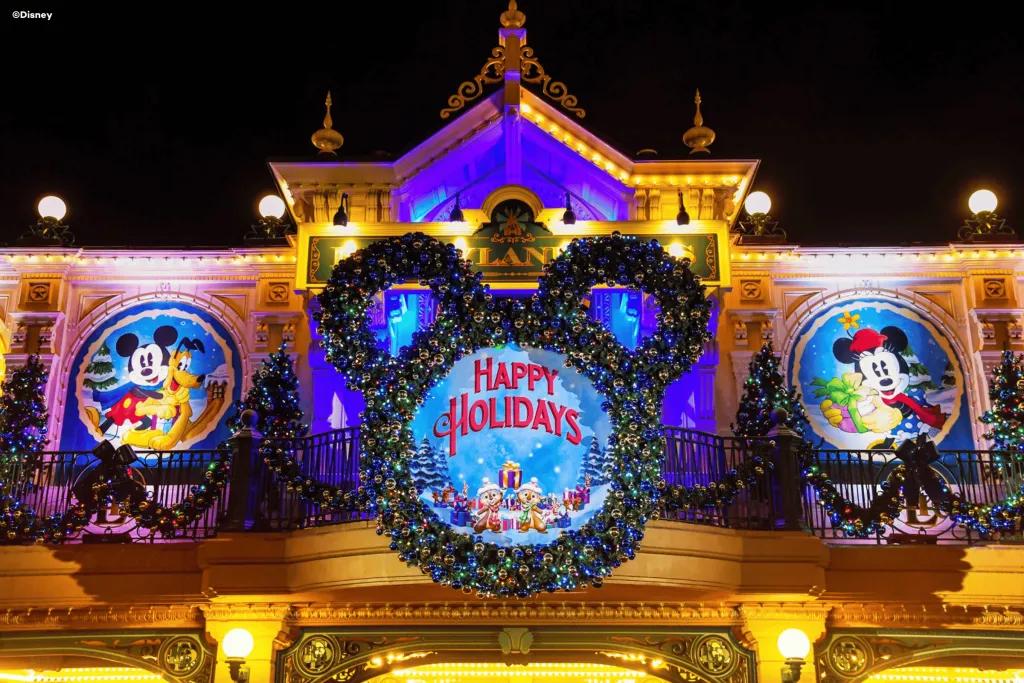 A Christmas wreath in the shape of Mickey Mouse around a sign reading Happy Holidays