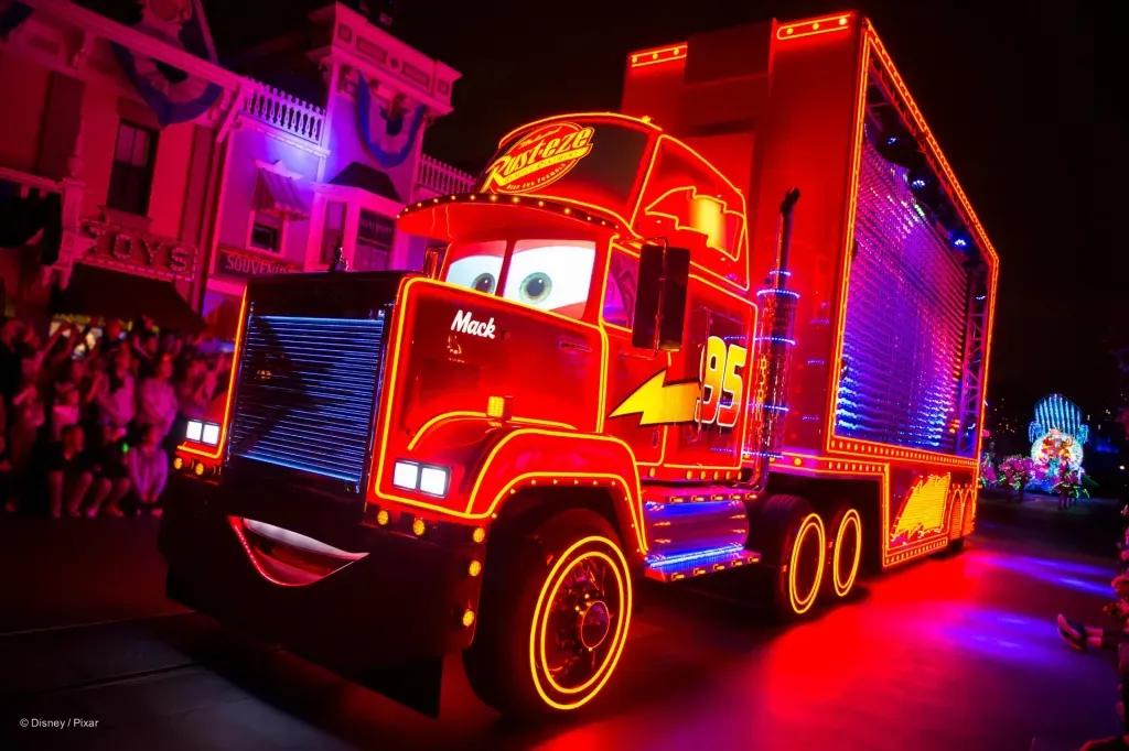 Hook aus Cars, ein riesiger roter Truck mit einem grinsenden Gesicht auf der Vorderseite, leuchtet in rotem Neonlicht. Er ist mit gelben Blitzen geschmückt.