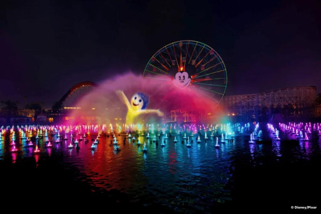 Joy from Inside Out projected onto a water fountain with a Mickey Mouse ferris wheel in the background