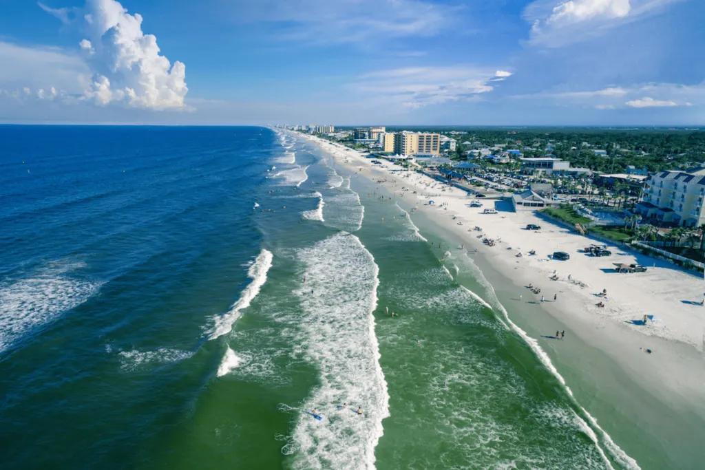 Waves in the clear blue ocean crashing towards the sandy beach.