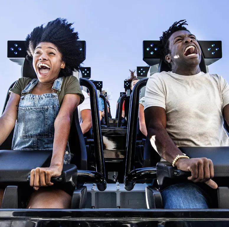 A man and woman shout with excitement on the Jurassic World VelociCoaster at Universal Islands of Adventure.