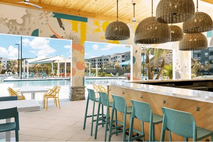 Outdoor bar and grill seating area overlooking the pool at Villatel Orlando Resort