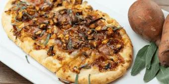 A long pizza topped with autumnal ingredients