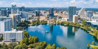 Modern buildings surrounding a large lake. Including a mix of smaller buildings and tall towers.