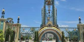 Grand entrance with a semicircle portal opening and above there's a statue of a planet and star constellation.