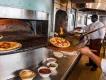 A chef taking a pizza out of a wood fired pizza oven at California Grill