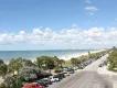 A view down a road running along a white sandy beach and blue ocean