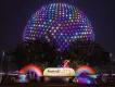 Spaceship Earth lit up in rainbow colours behind a sign reading Festival of the Arts