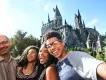 Selfie of family of four stood on bridge in front of the Hogwarts Castle. There is a boy holding the camera, besides him is a young woman, an older woman and an older man. All are smiling with joy.