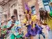 Menschen tanzen mit Mardi Gras Künstlern in bunten, mit Federn geschmückten Kostümen