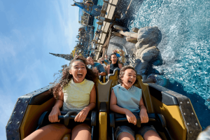 Riders laughing and screaming as their coaster splashes through water on Hiccup's Wing Gliders, Isle of Berk
