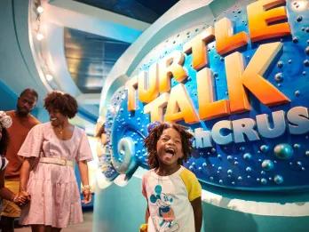 A young boy with his mouth open in excitement in front of a sign reading Turtle Talk with Crush