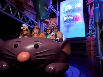 A family in a ride vehicle shaped like a large cartoon rat