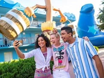 Three friends taking a selfie in front of a large broomstick holding buckets like in Fantasia