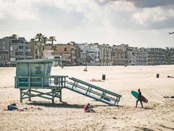 Beach with a wooden lifeguard shack and colourful houses lining the beach front.