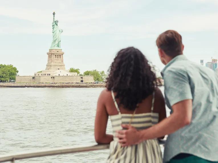 Couple looking at the Statue of Liberty from the deck of a ferry