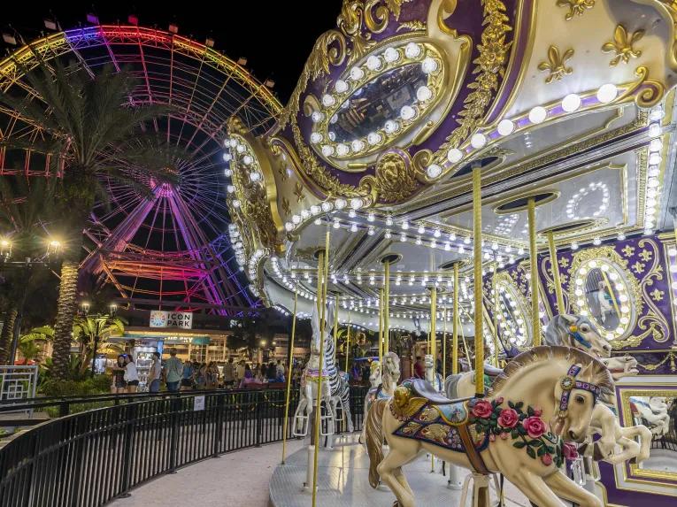 Carousel in front of the Icon Orlando Wheel illuminated at night