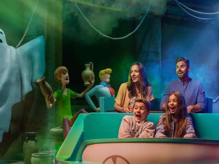 Guests enjoying the Scooby-Doo: The Museum of Mysteries ride at Warner Bros. World Abu Dhabi, laughing in a ride vehicle as a friendly ghost figure floats nearby.