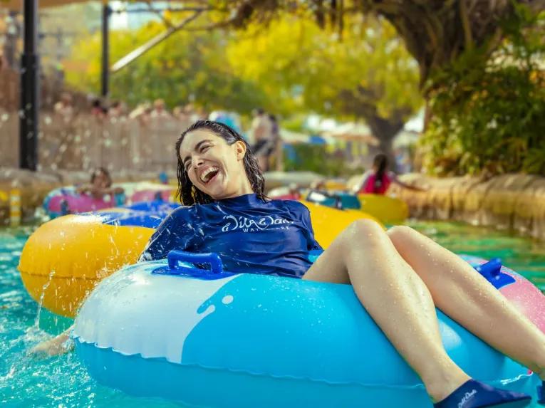 Woman smiling on a rubber ring, floating through the water at Wild Wadi Waterpark